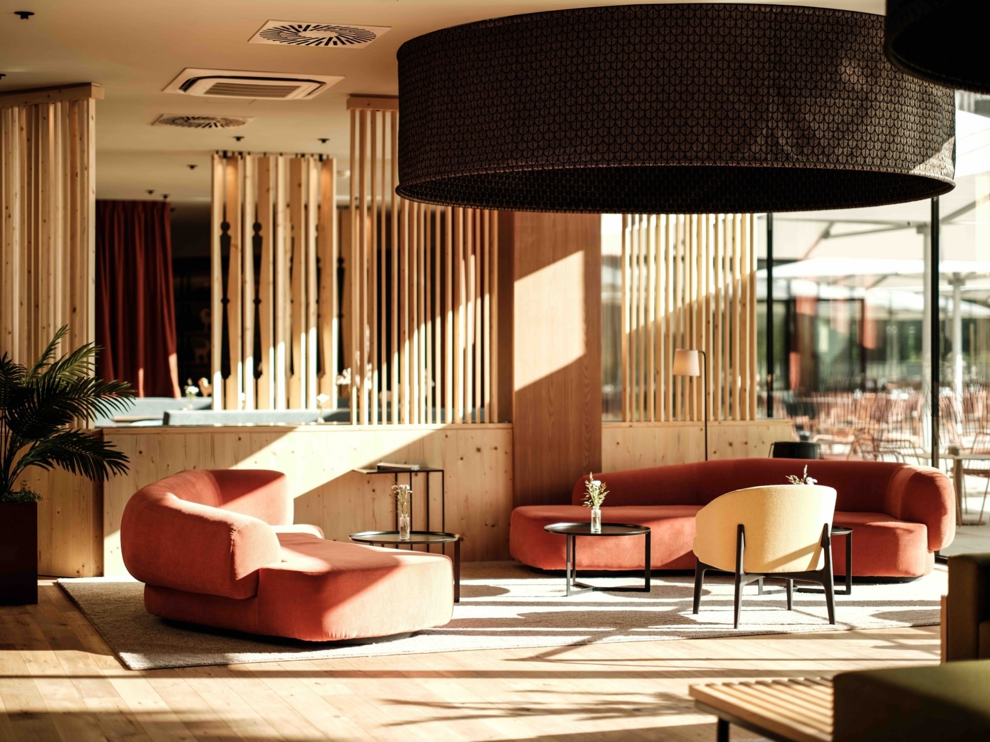 Hotelové lobby spojuje přírodní dřevo teplé barvy a oblé tvary nábytku do útulného prostoru jako stvořeného pro odpočinek