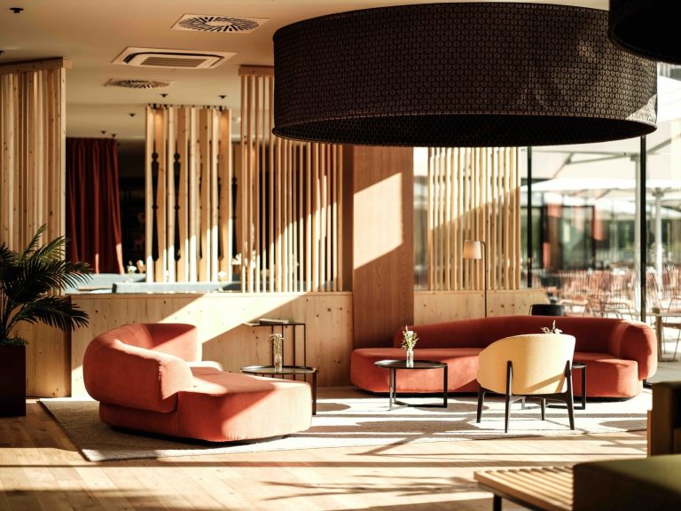 Hotelové lobby spojuje přírodní dřevo teplé barvy a oblé tvary nábytku do útulného prostoru jako stvořeného pro odpočinek